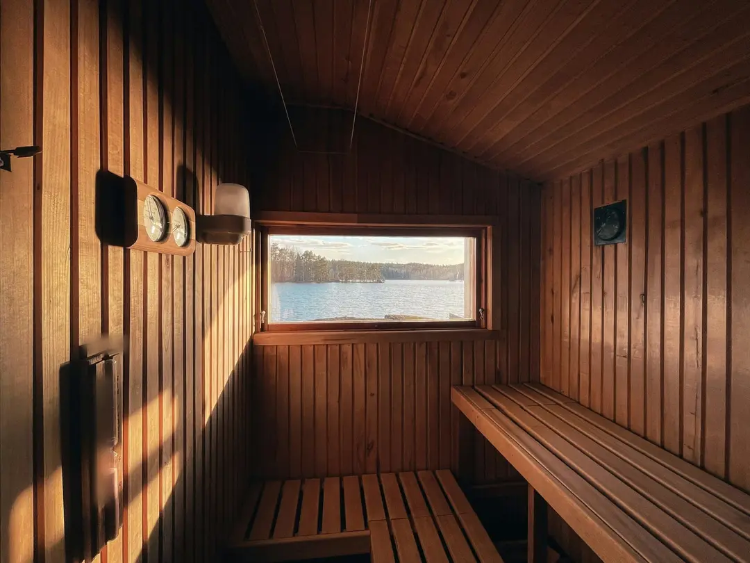 Holzsauna im goldenen Abendlicht mit Fenster zum Waldsee